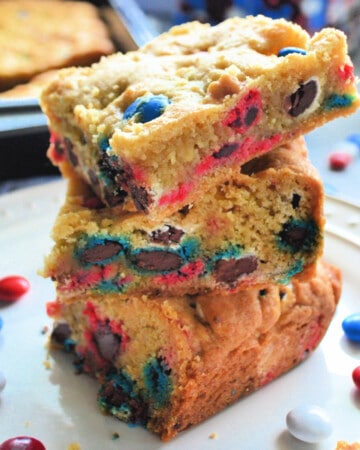 Three cookie bars stacked with red white and blue M&M's on a white plate.