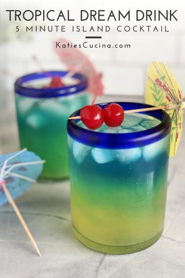 Two yellow, green, blue layered drinks with 2 maraschino cherries on top.