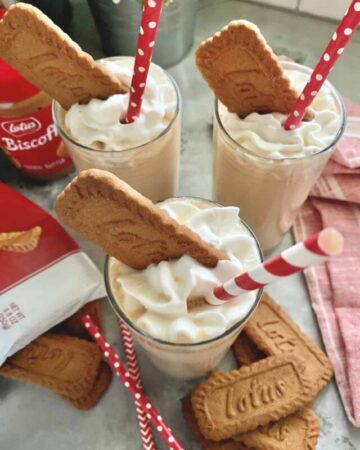 Three milkshakes in glasses, topped with whipped cream and Biscoff cookie