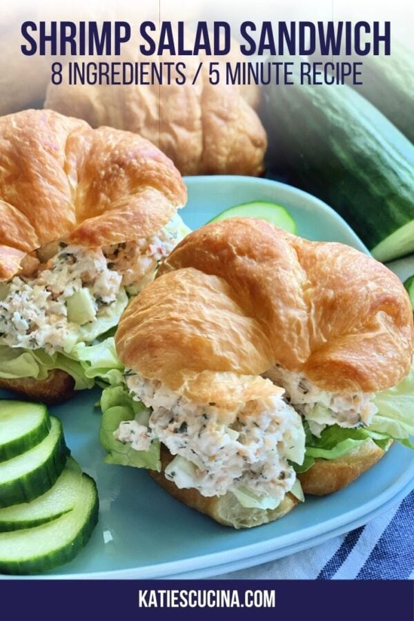 Two shrimp salad croissants on a blue square plate with cucumber slices.