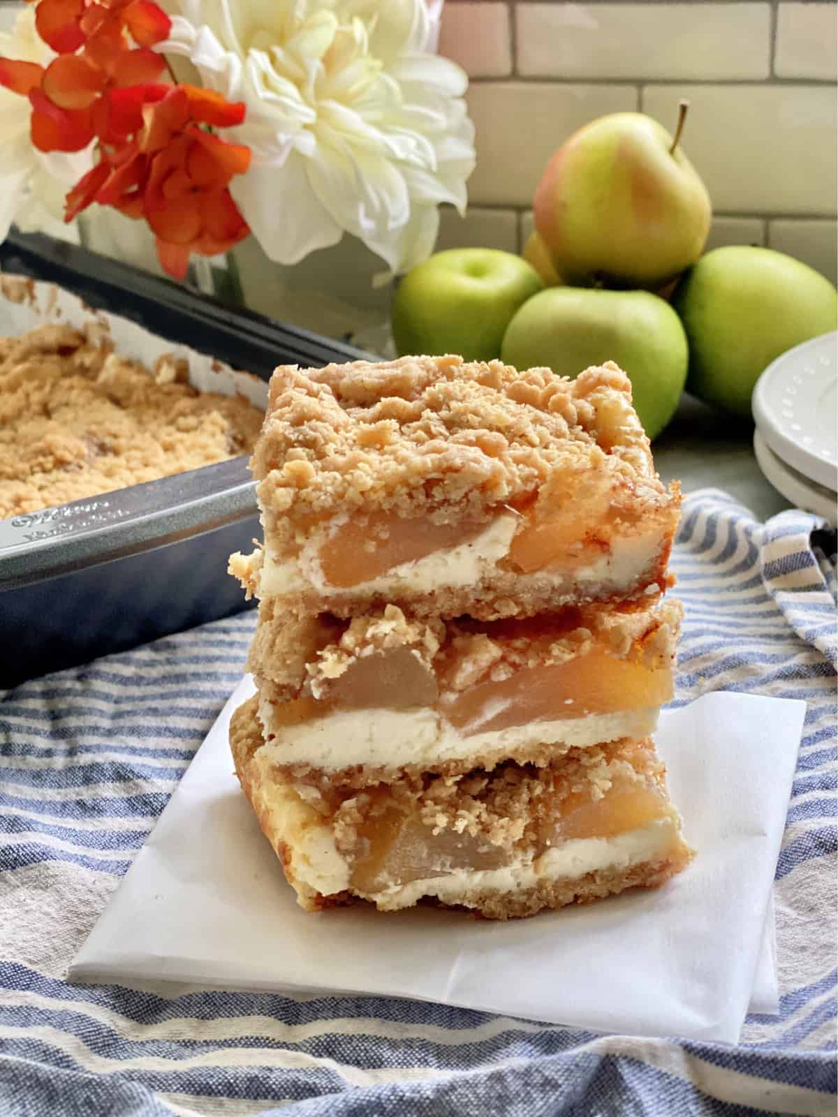 Three cheesecake bars filled with apple sitting on a piece of parchment paper. 