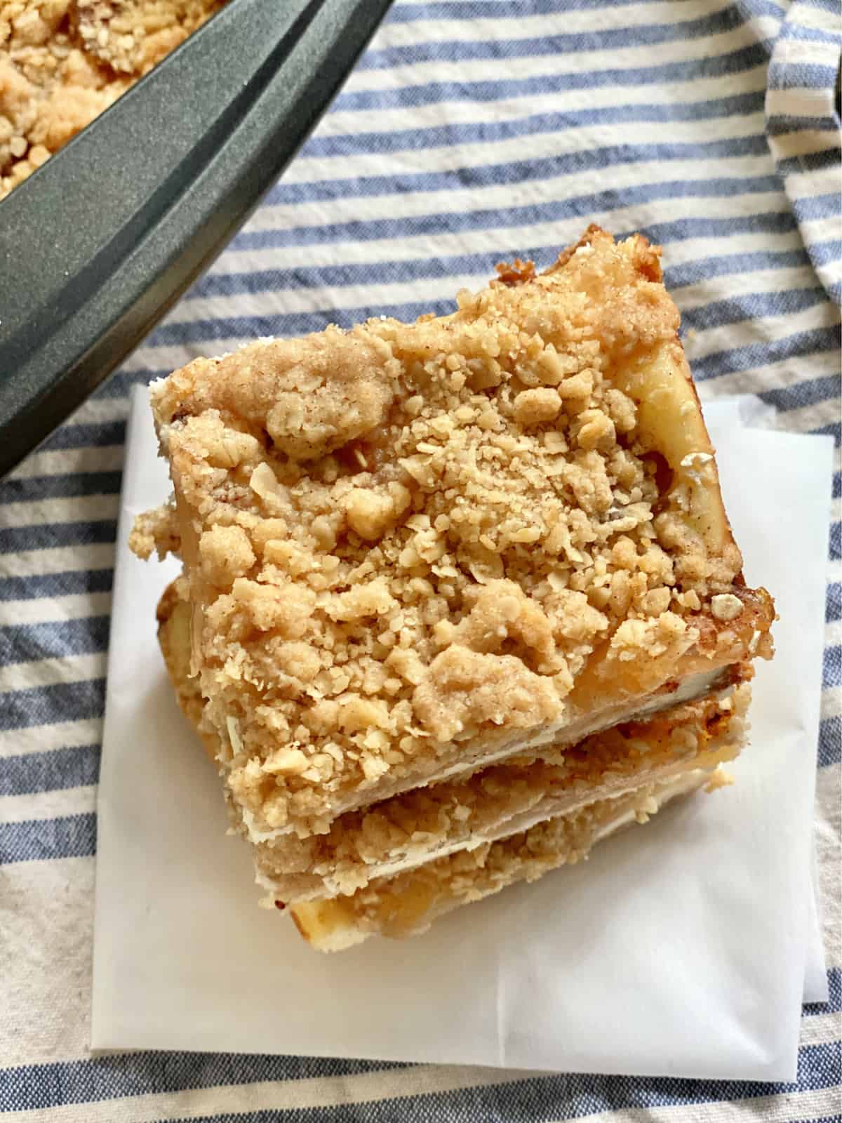 Top view of three cut cheesecake bars with crumble topping sitting on parchment paper.