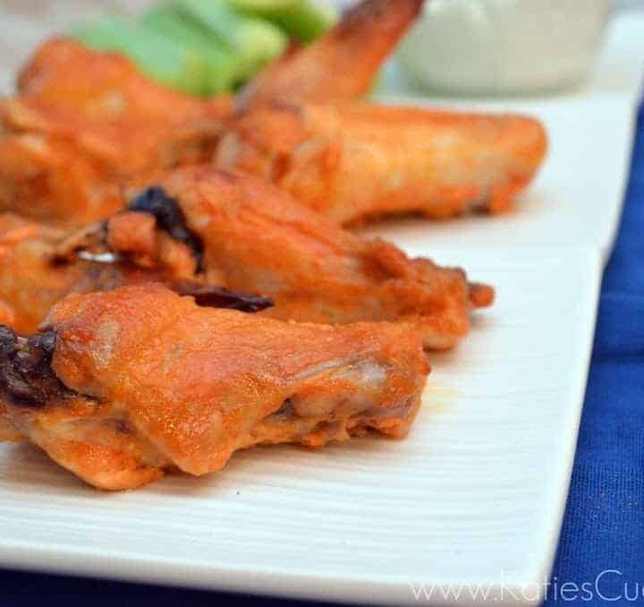 Baked spicy orange buffalo wings and drums on a white platter.