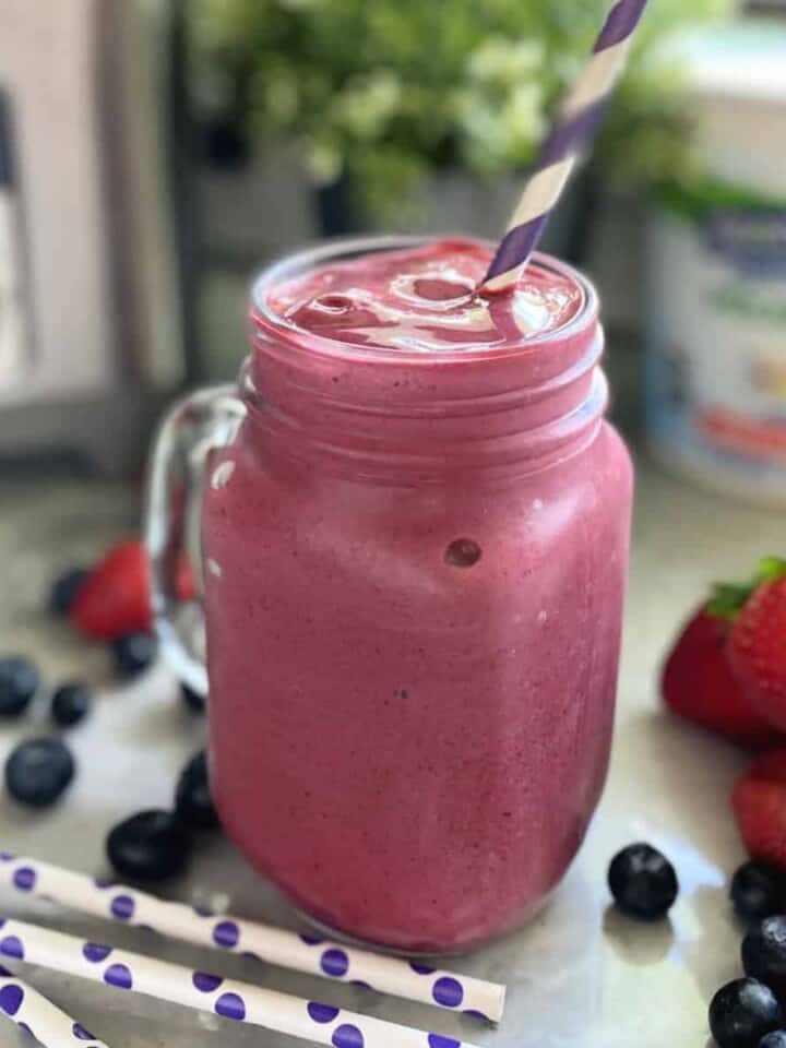 Close up of a purple smoothie is a mason jar style glass.