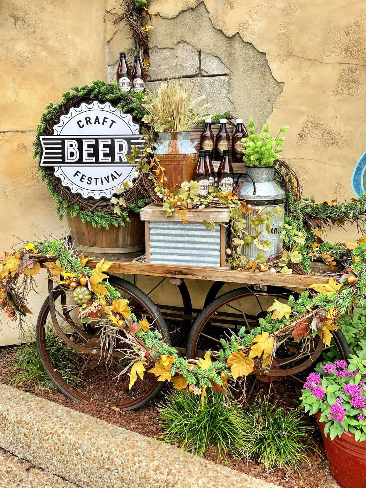 Wagon outside draped with leaves and foliage with craft beer festival sign and beer bottles.