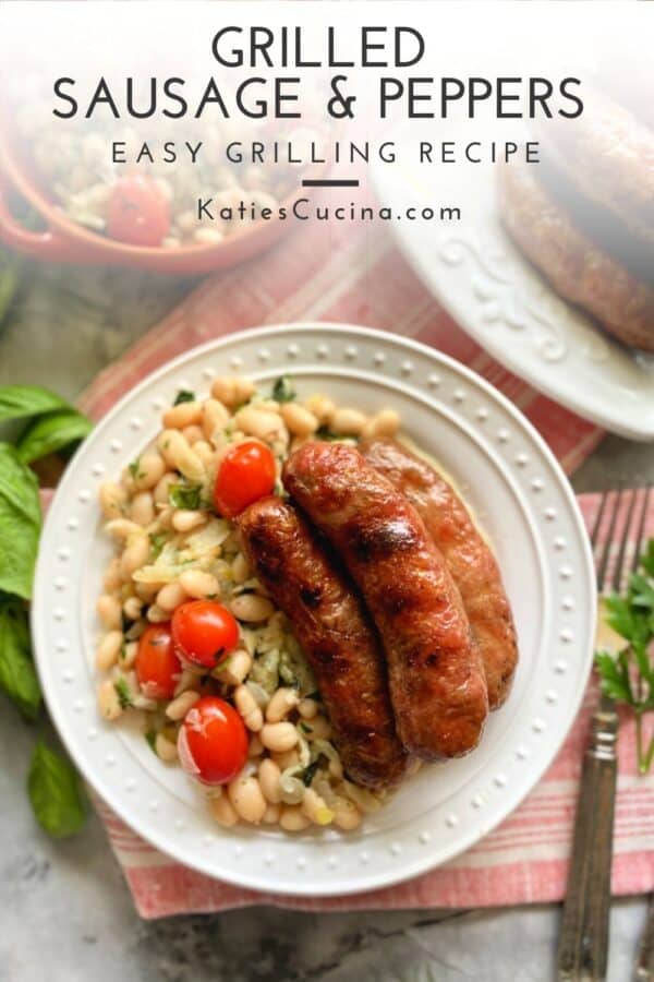 Top view of white plate with white beans and three sausage links on top with text on image for Pinterest.