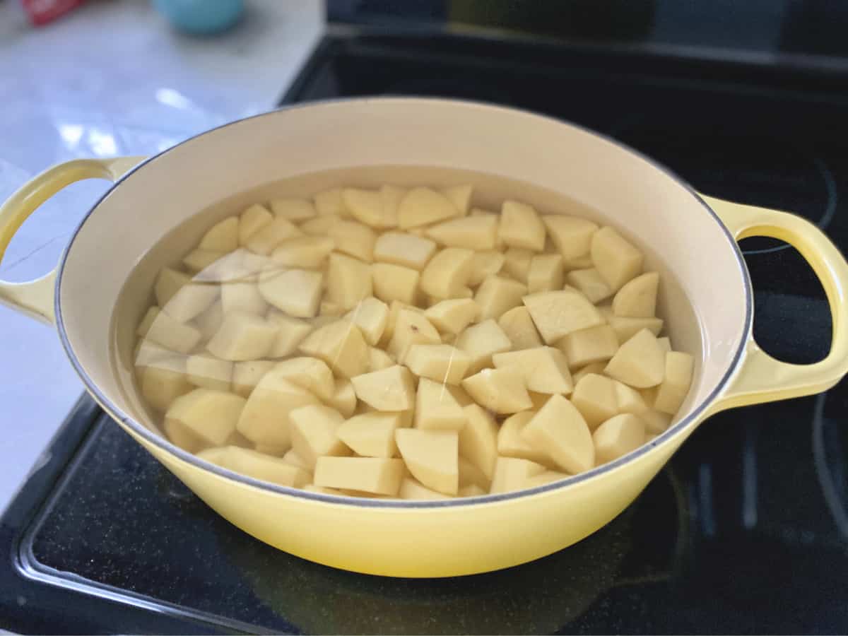 Peeled diced potatoes in a cast iron yellow pot.