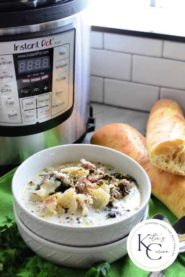 Two white bowls stacked filled with soup, bread and Instant Pot in background.