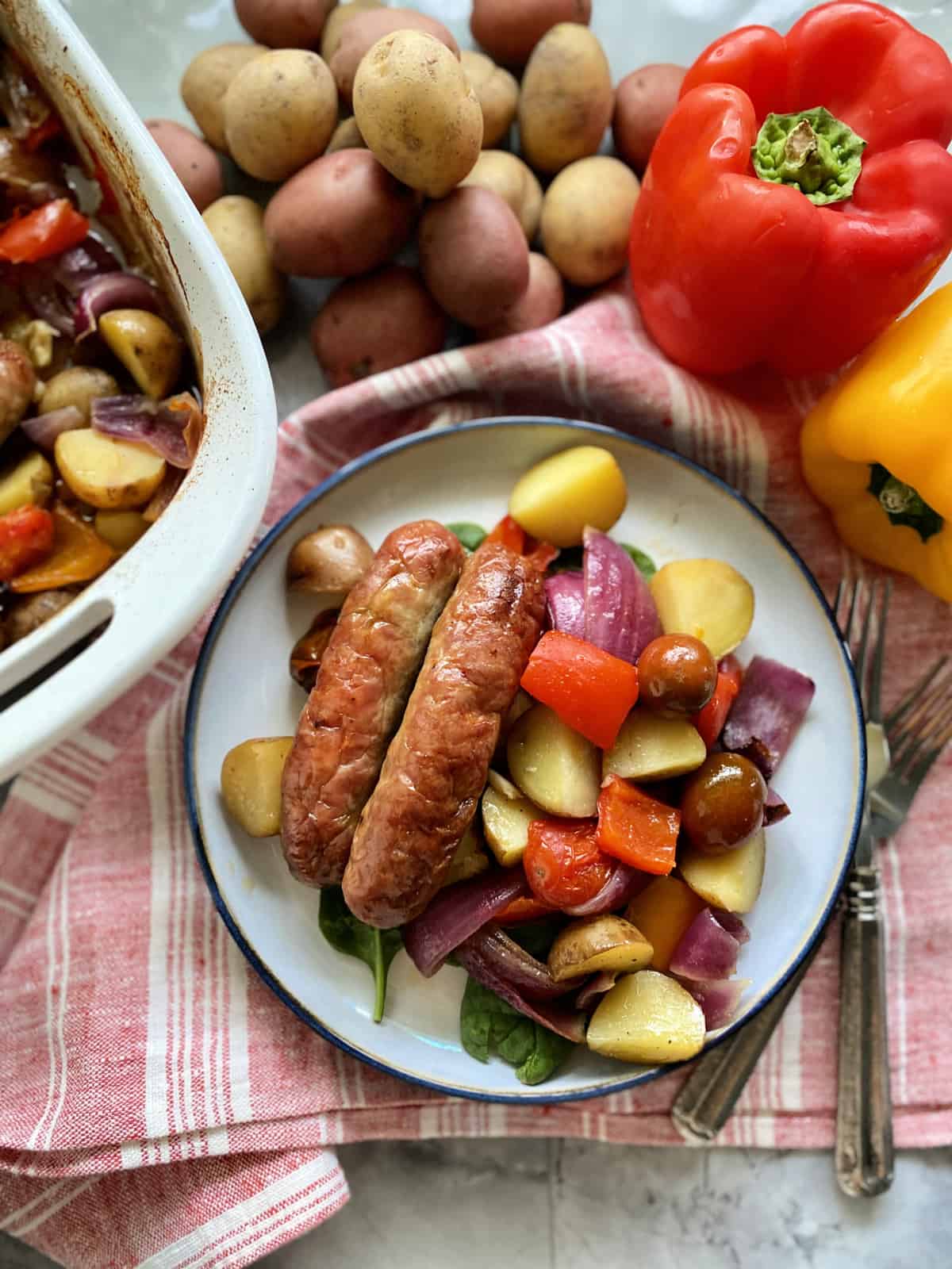 Top view of a plate of Italian sausage with potatoes, bell peppers, and onions.