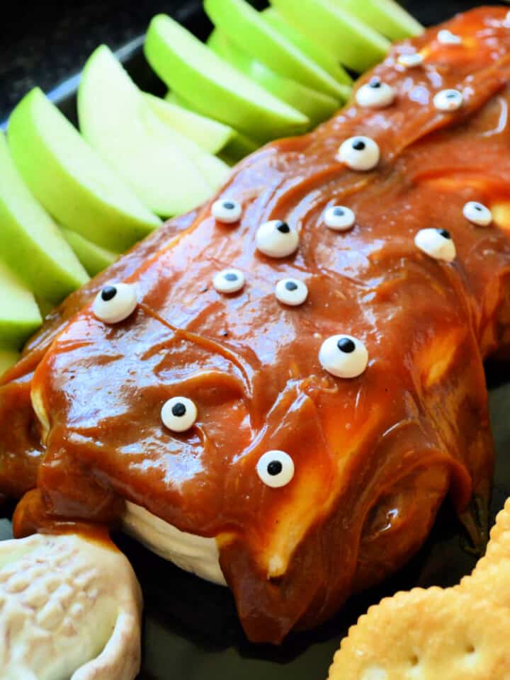 Cream cheese with carmel on top and eyeballs with apples and crackers on a tray.