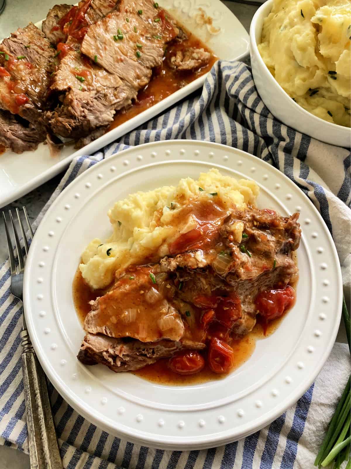 Top view of a plated pork roast dinner with mashed potatoes and gravy.