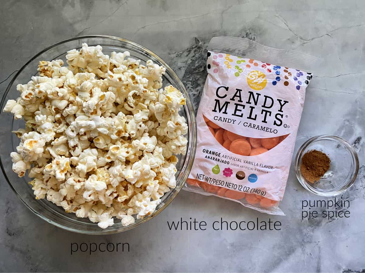 Ingredients on marble countertop: popcorn, white chocoalte, and pumpkin spice.