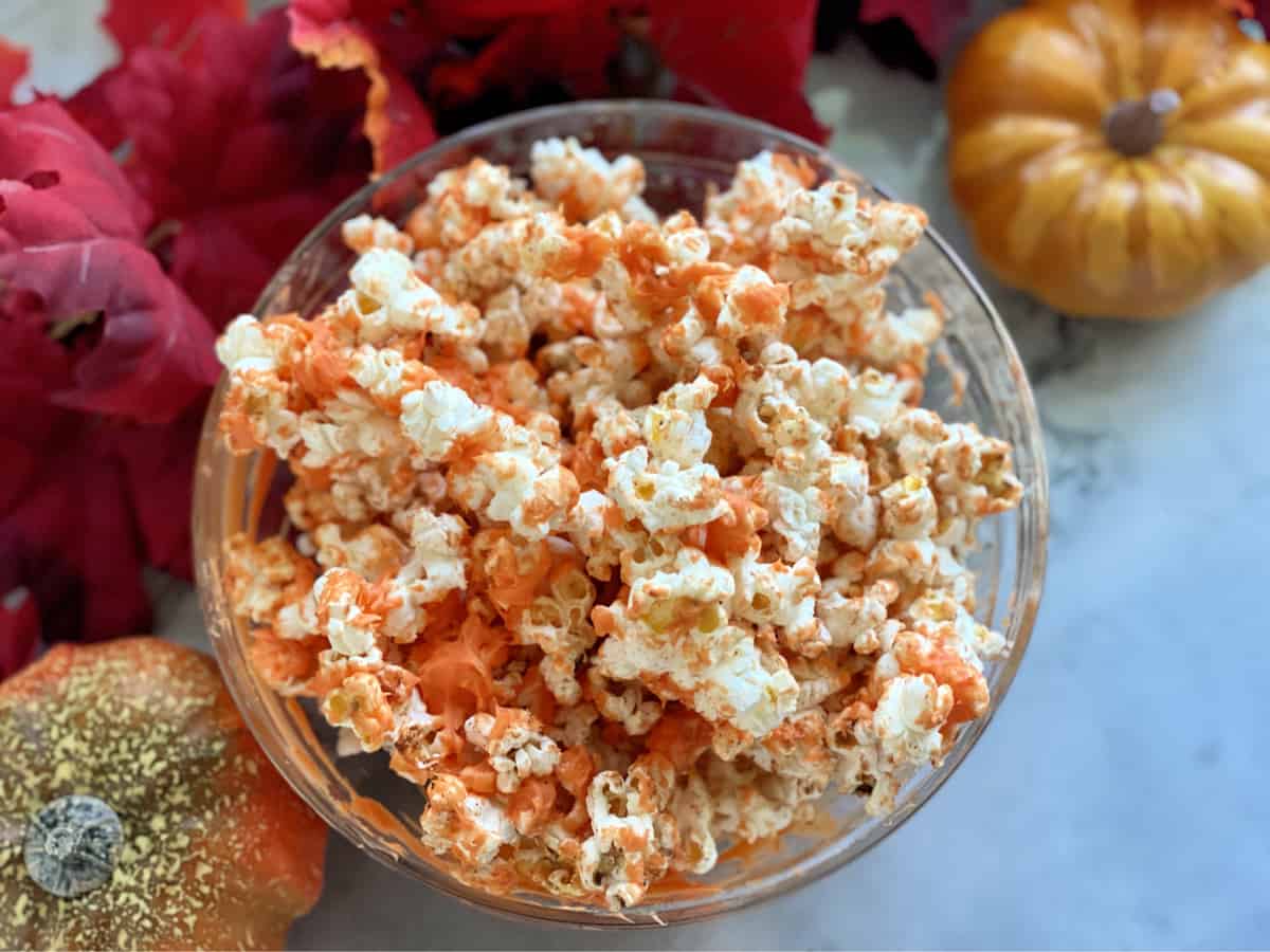 Glass bowl with popcorn coated with orange white chocolate.