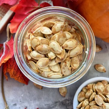 Top view of a glass jar fileld with roasted pumpkin seeds.