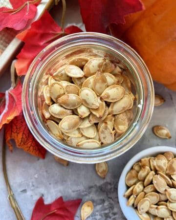 Top view of a glass jar fileld with roasted pumpkin seeds.