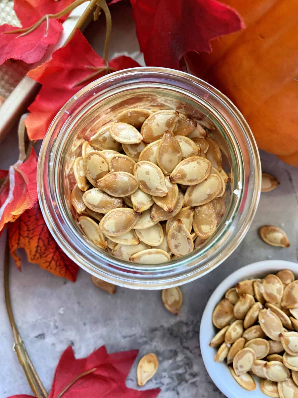 Top view of a glass jar fileld with roasted pumpkin seeds.