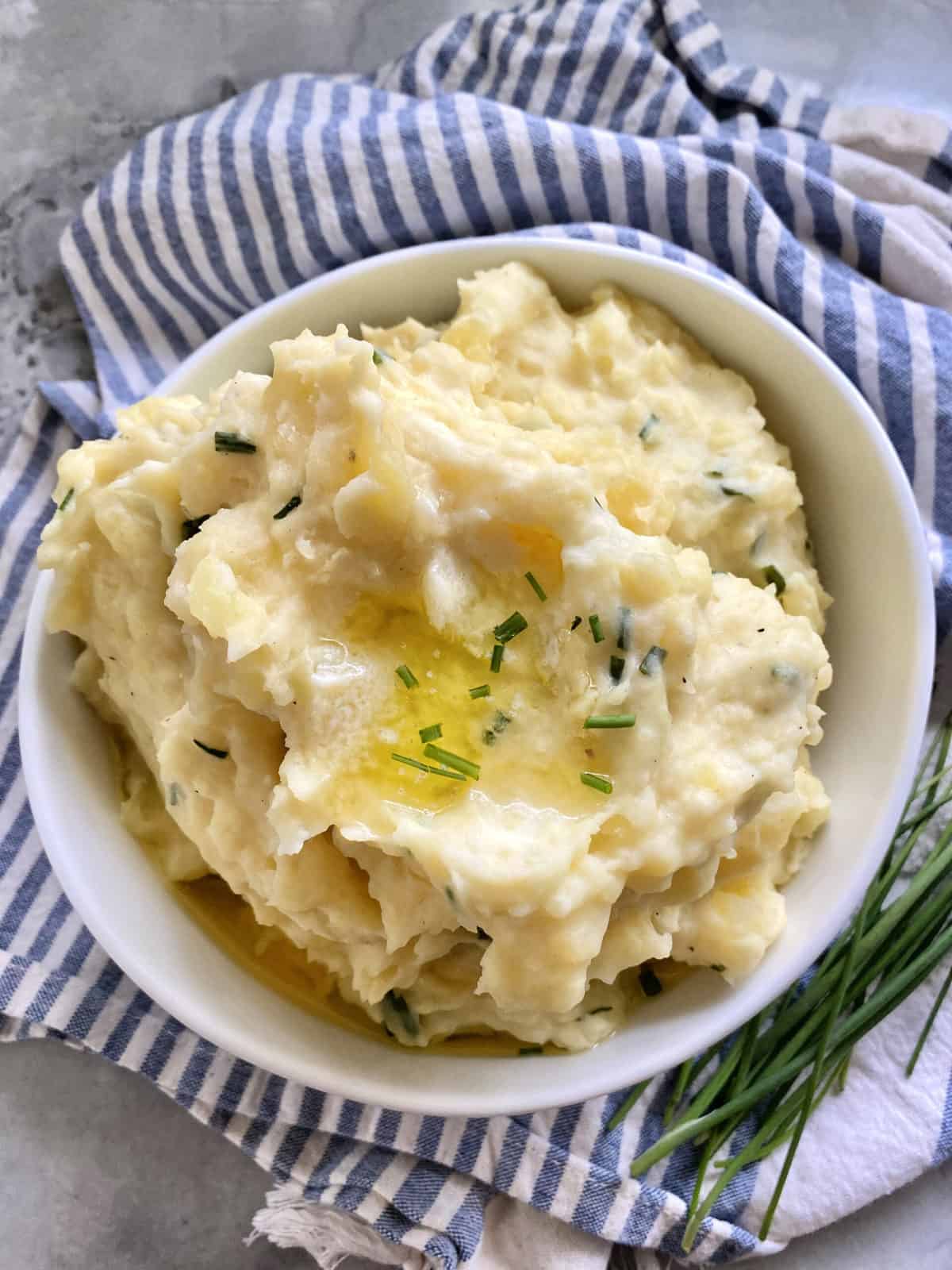 Top view of mashed potatoes in a bowl sitting on a blue and white cloth.