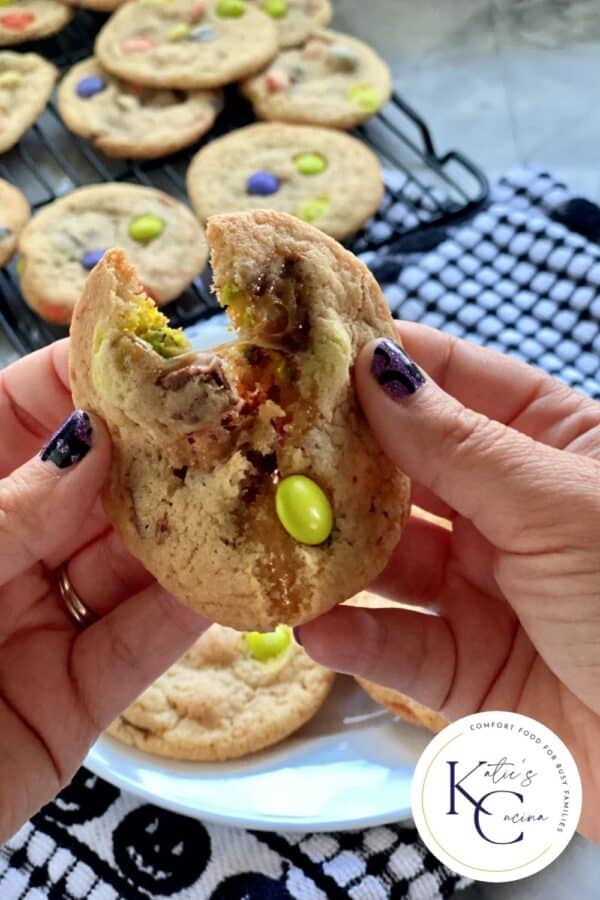 Female hand with purple nails pulling apart a candy cookie with logo on corner.