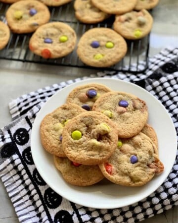 Plate of cookies with a wire rack in background with more cookies.