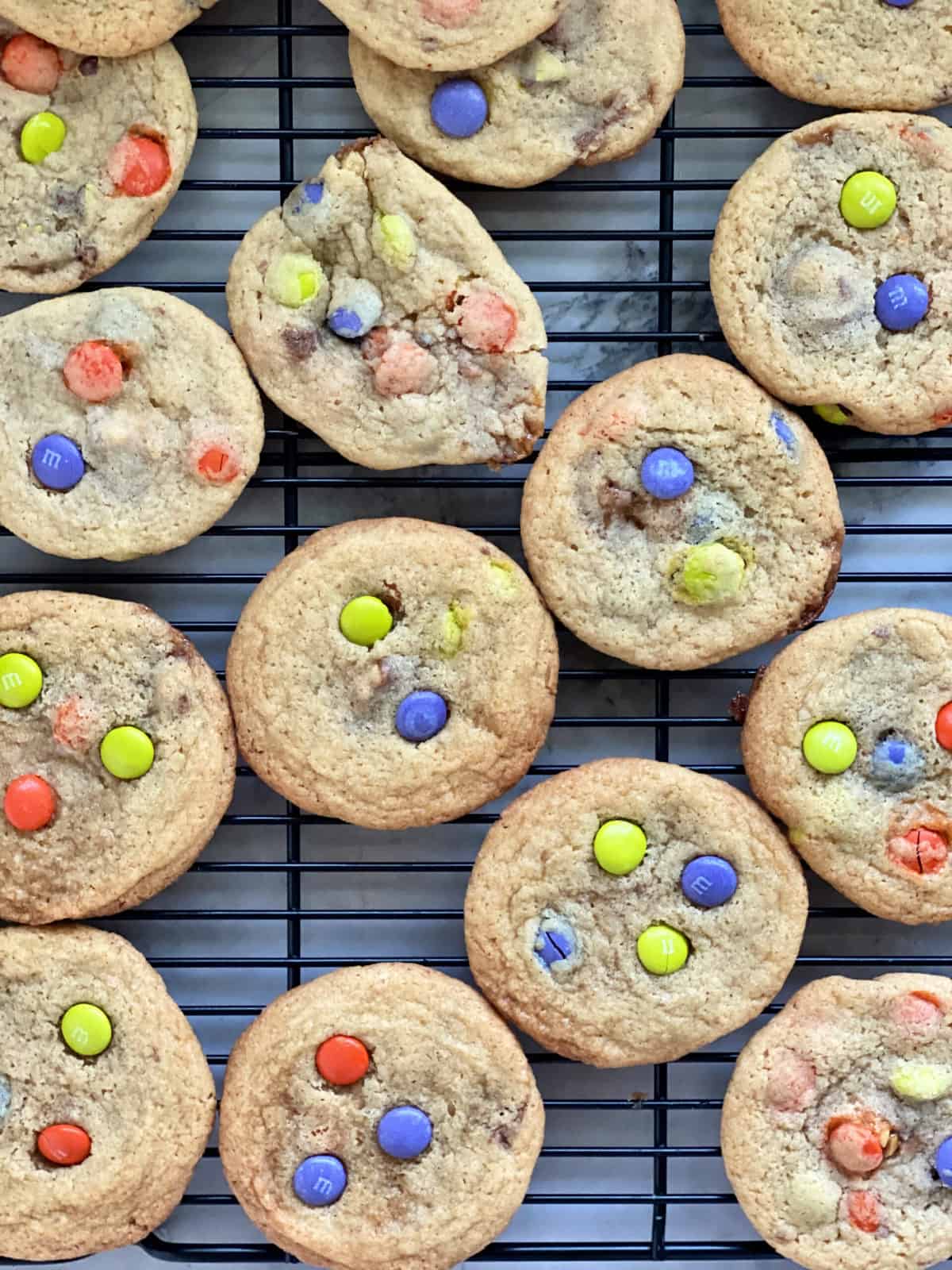 Top view of M&M cookies on a black wire rack.