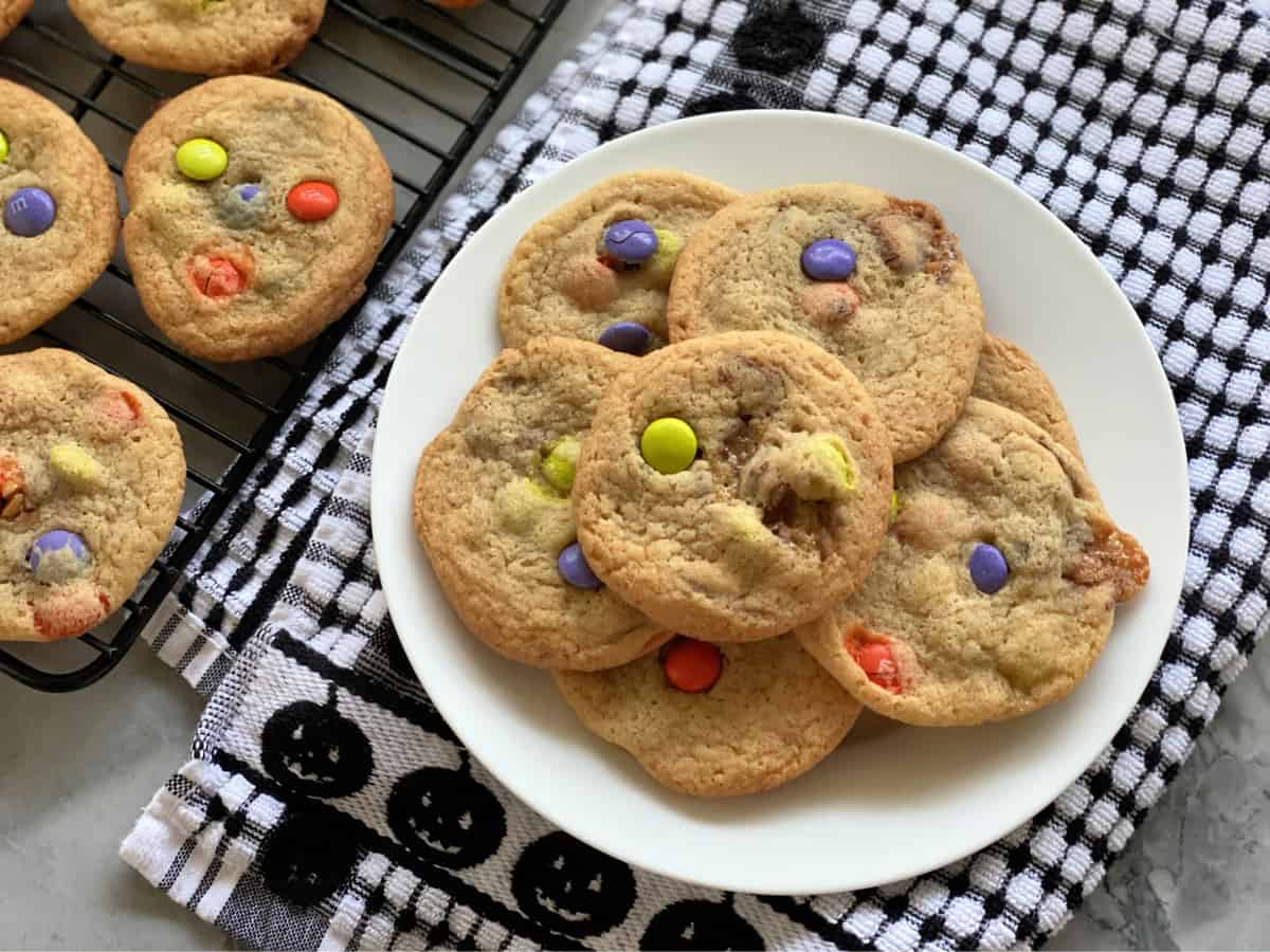 White plate of cookies with candies sitting on a black an white checkered dish towel.