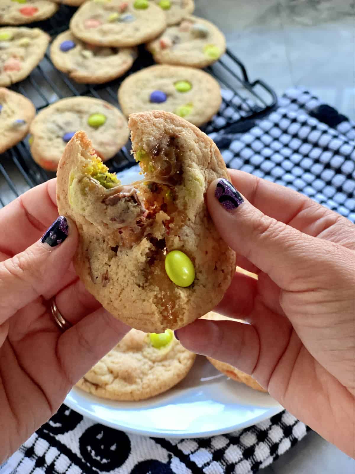 Female hand with purple nails pulling apart a candy cookie.