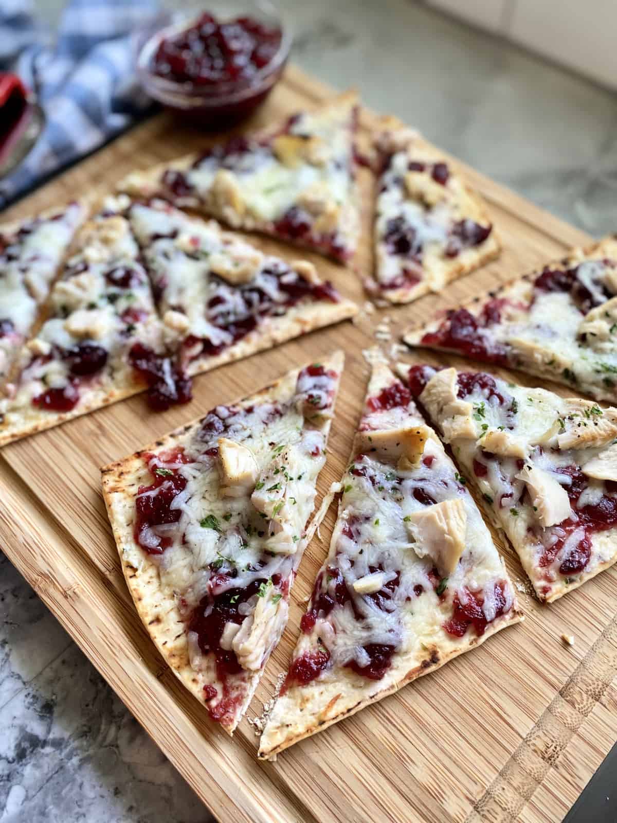 Two triangle sliced flatbreads laying on a wood cutting board.