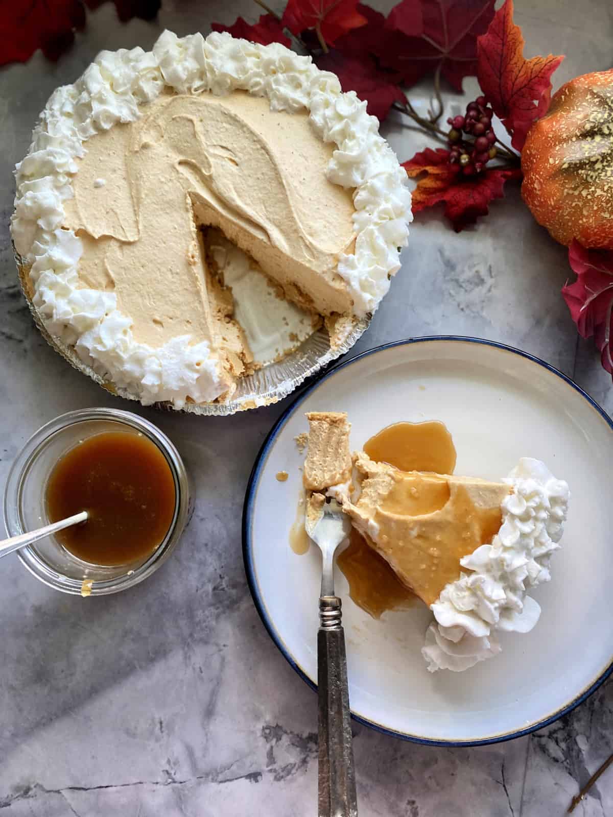 Pumpkin Cheesecake Pie with a slice on a plate drizzled with caramel sauce.