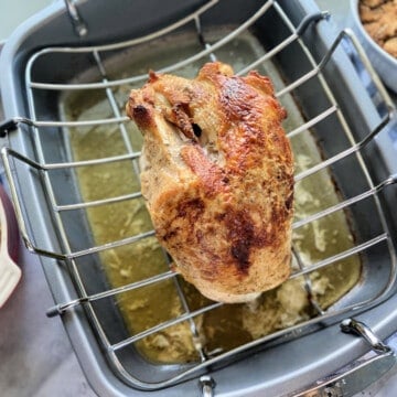 Grey roasting rack with a turkey breast on top.