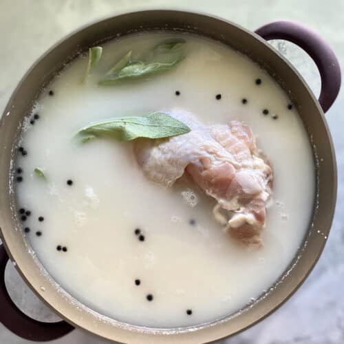 Top view of sage leaves in a buttermilk brine with raw turkey.