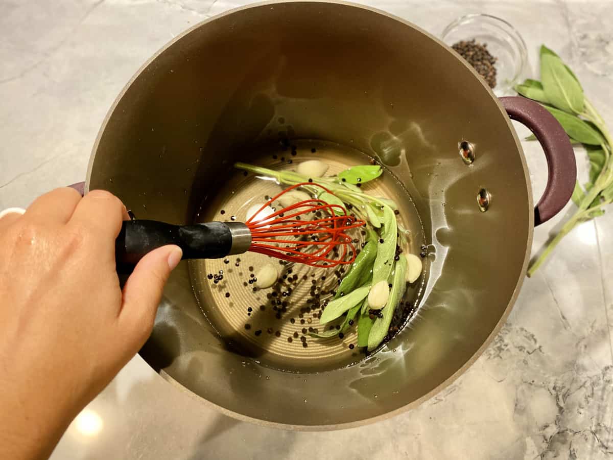 Female hand whisking water to mix salt and herbs.