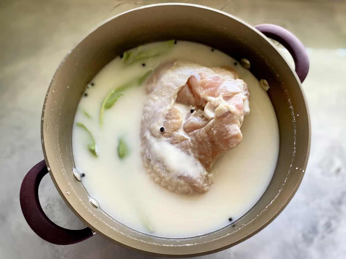 Top view of a buttermilk brine with sage, peppercorns, and a raw turkey.