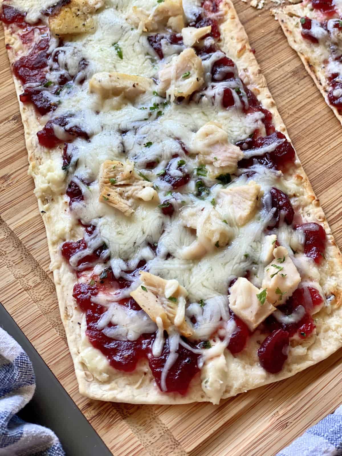 Top view of a single flatbread with turkey, mozzarella and cranberry sauce.