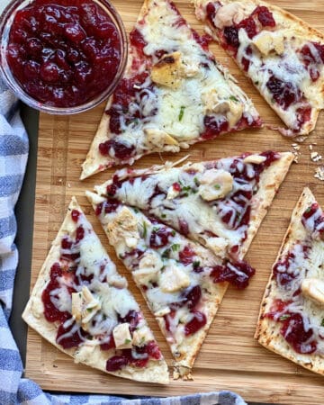 Top view of four triangle slices of flatbread with cranberry sauce on the side.