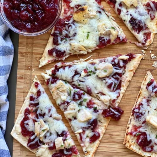 Top view of four triangle slices of flatbread with cranberry sauce on the side.