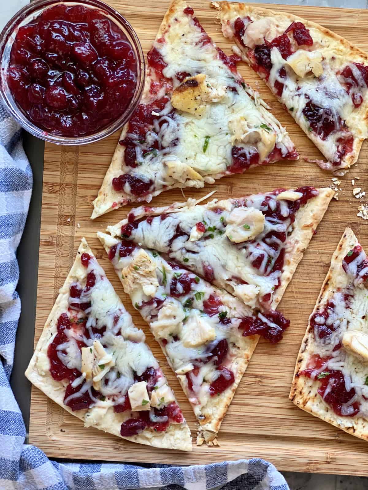 Top view of four triangle slices of flatbread with cranberry sauce on the side.