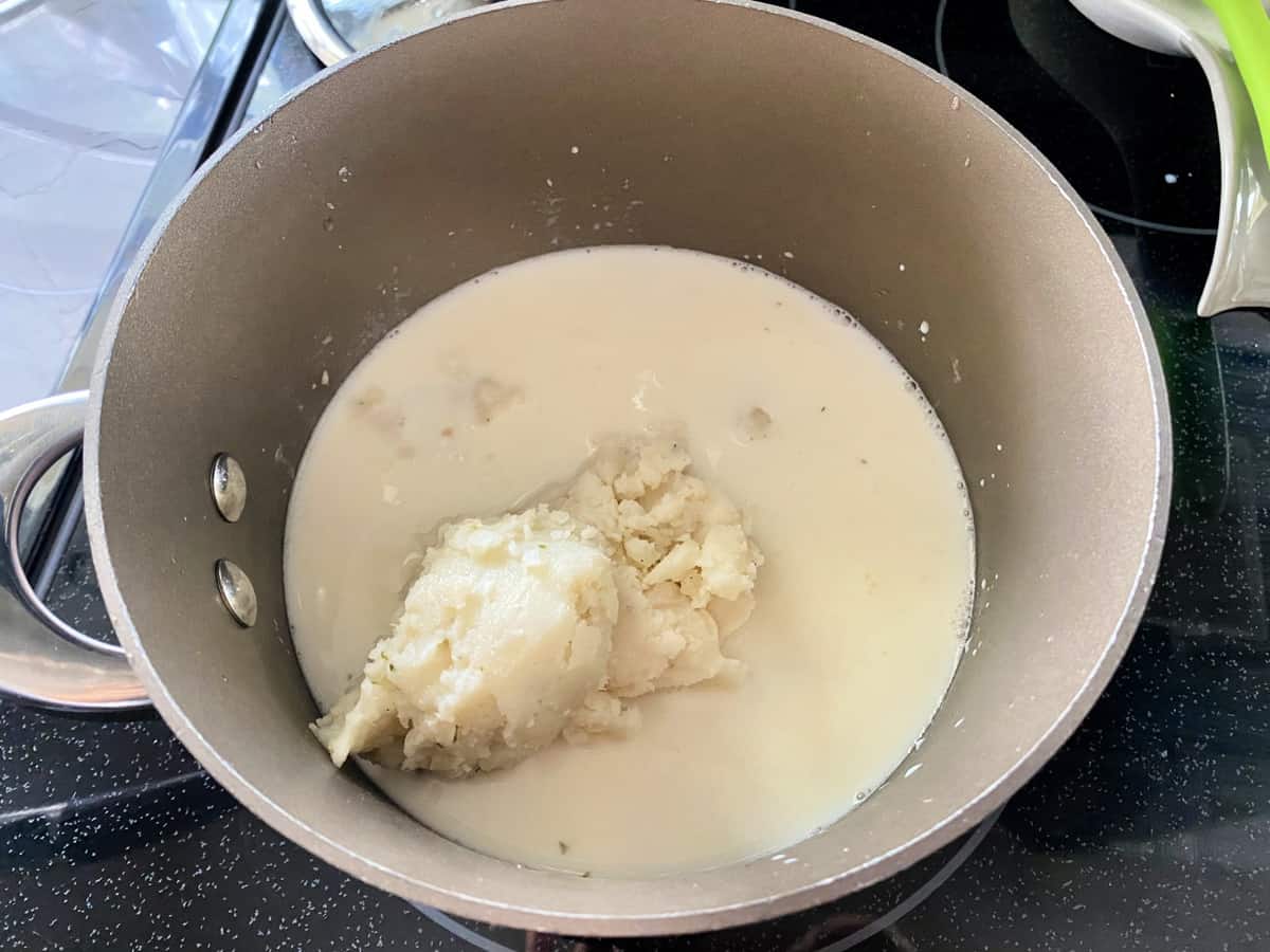 Mashed potatoes in a sauce pan filled with milk.