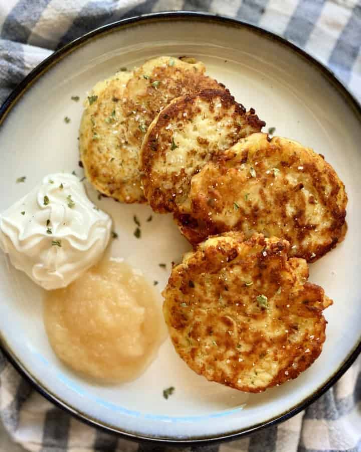 Top view of a plate of mashed potato cakes on a plate with toppings.