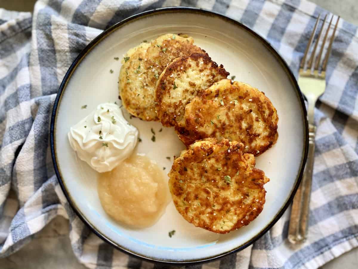 Top view of a plate of mashed potato cakes on a plate with toppings.