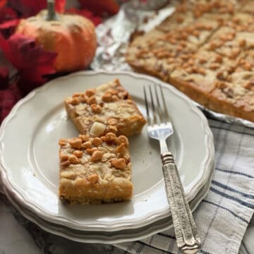 Two pumpkin pie bars on two plates with a fork.