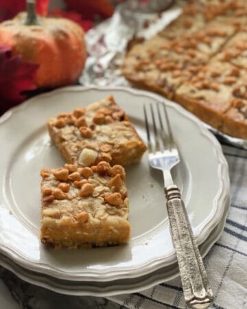 Two pumpkin pie bars on two plates with a fork.