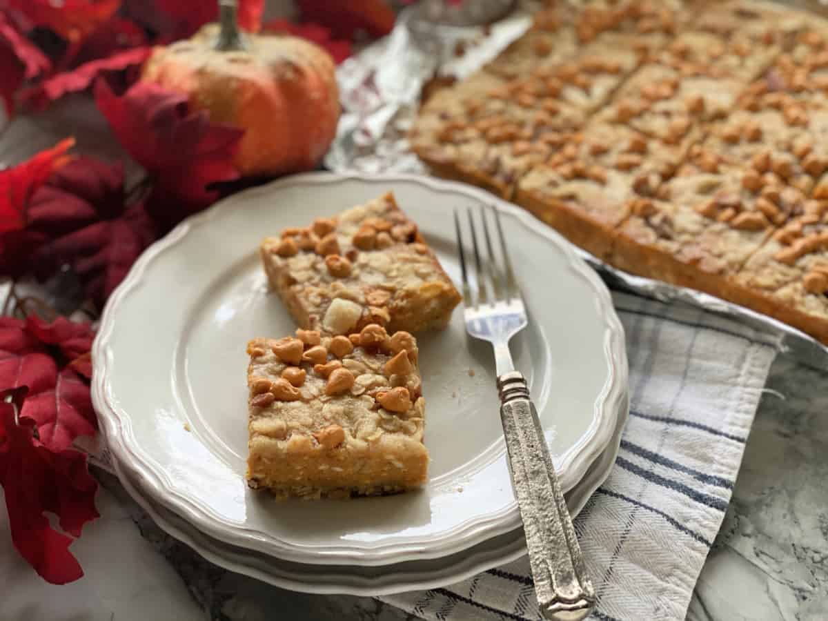 Two pumpkin pie bars on two plates with a fork.