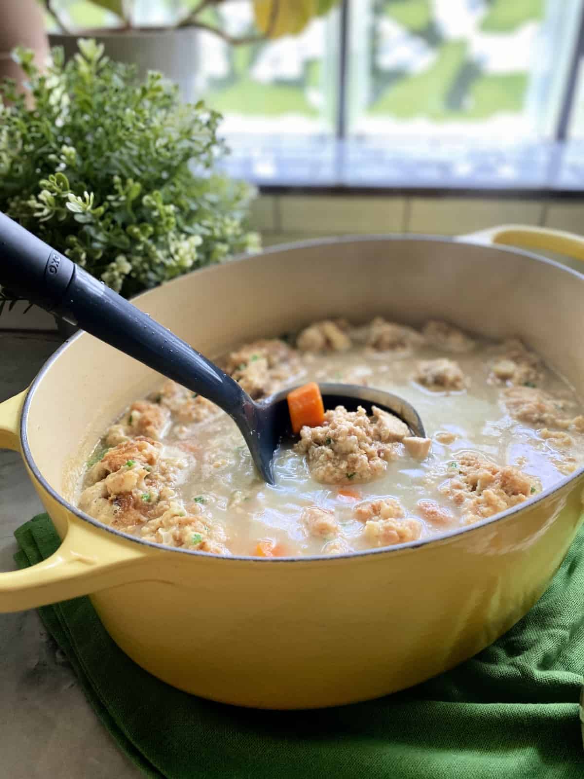 Yellow pot with black ladle scooping out Turkey and Stuffing Dumpling Soup.