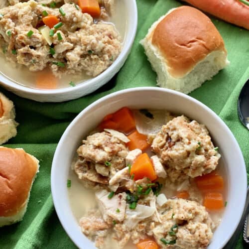 Top view of two bowls of Turkey and Stuffing Dumpling Soup with dinner rolls on the side.