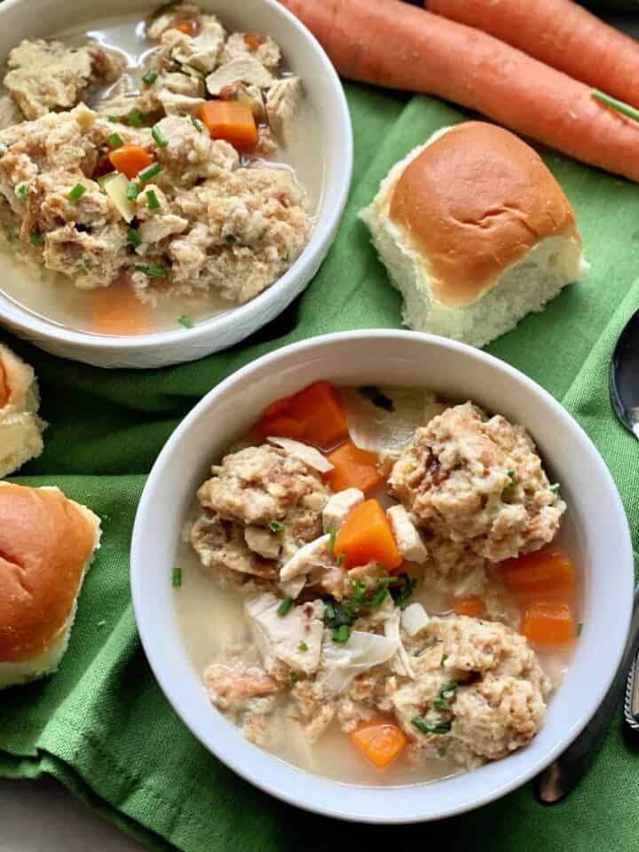 Top view of two bowls of Turkey and Stuffing Dumpling Soup with dinner rolls on the side.