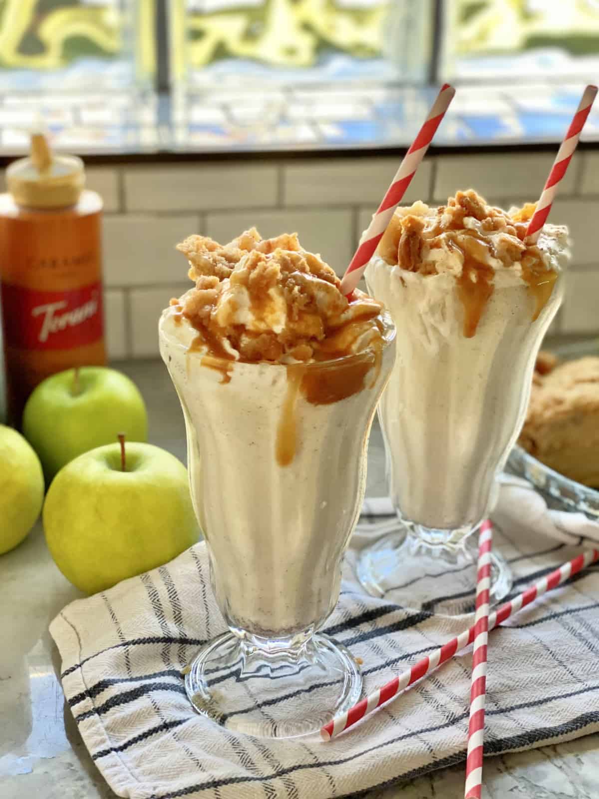 Two tall glasses filled with milkshakes topped with caramel sauce.