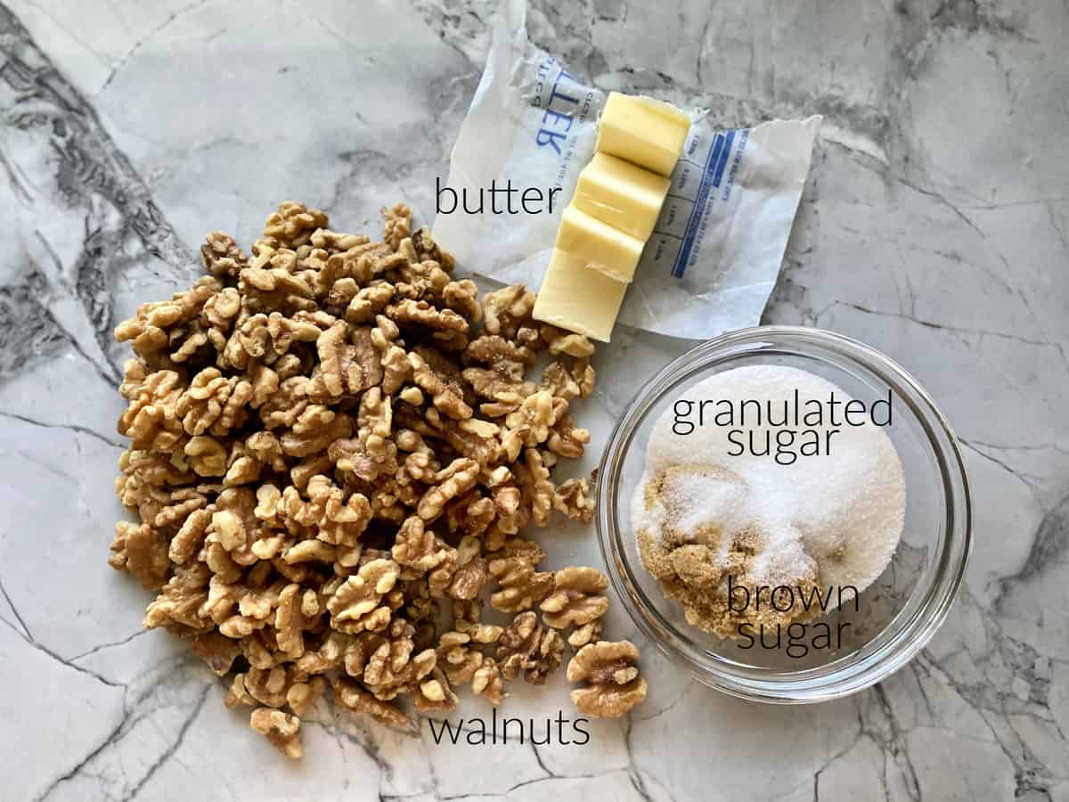 Ingredients: walnuts, butter, brown sugar, and granulated sugar in a glass bowl.