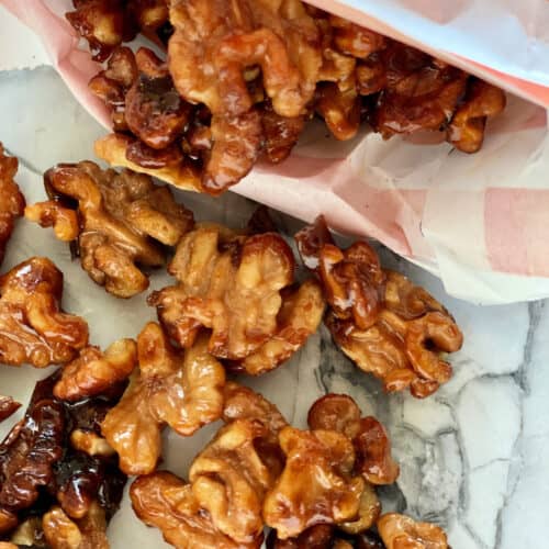 Close up of candied walnuts spilling out of an orange and white bag.