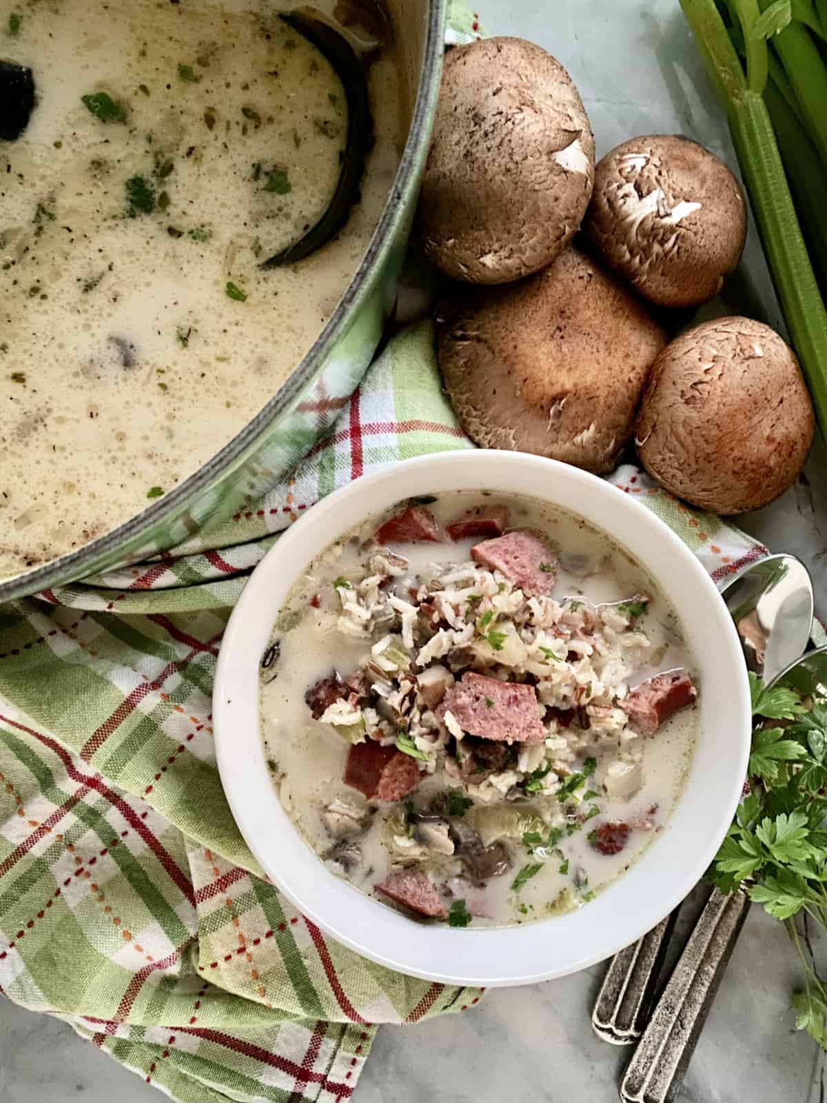 Top view of a pot of soup plus a bowl of sausage and rice soup.