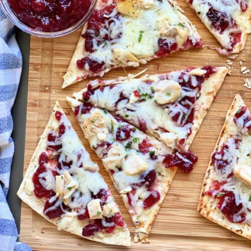 Wood cutting board with a flatbread sliced in triangles.